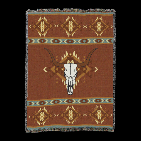 Rust cotton throw blanket with a single large longhorn steer skull centered over a spray of feathers, framed by teal and cream geometric bands at the