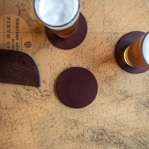 Burgundy leather coasters with cork backing on a nautical chart table with two beers