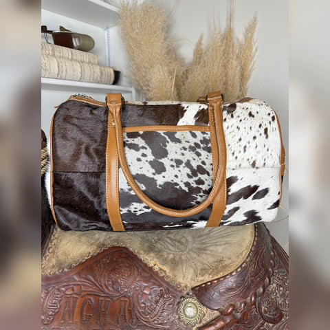 Patchwork hair-on cowhide weekender duffel bag in black, brown and white with tan leather handles
