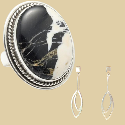 White buffalo ring and leaf dangle earrings jewelry set in sterling silver, shown on a desert plaster background