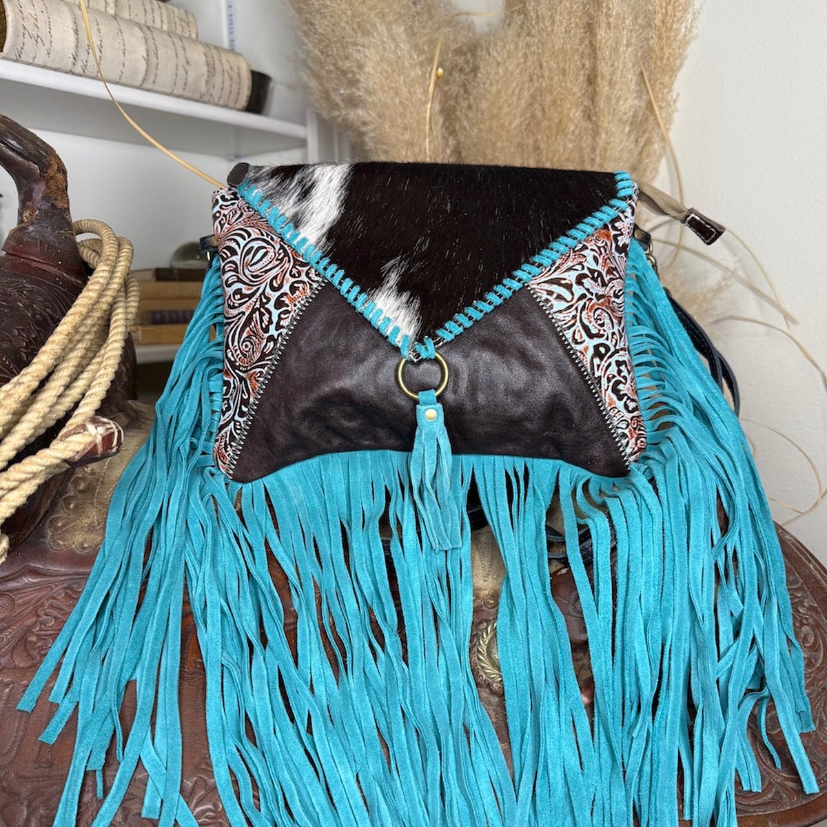 Cowhide and tooled leather shoulder bag with turquoise fringe, styled with western accessories