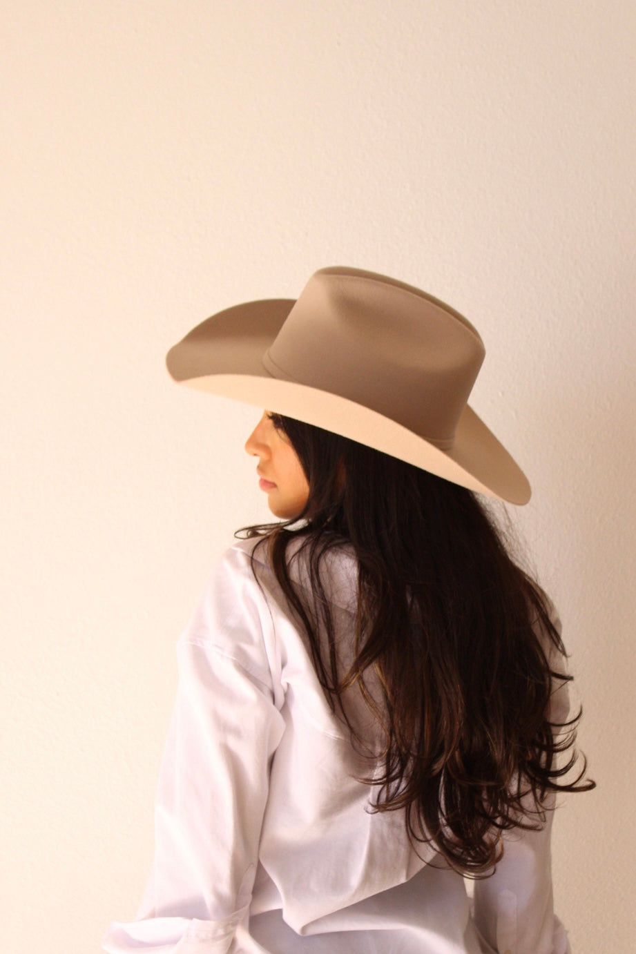 Model seen from behind wearing the desert sand Wren merino wool cowboy hat with long dark hair