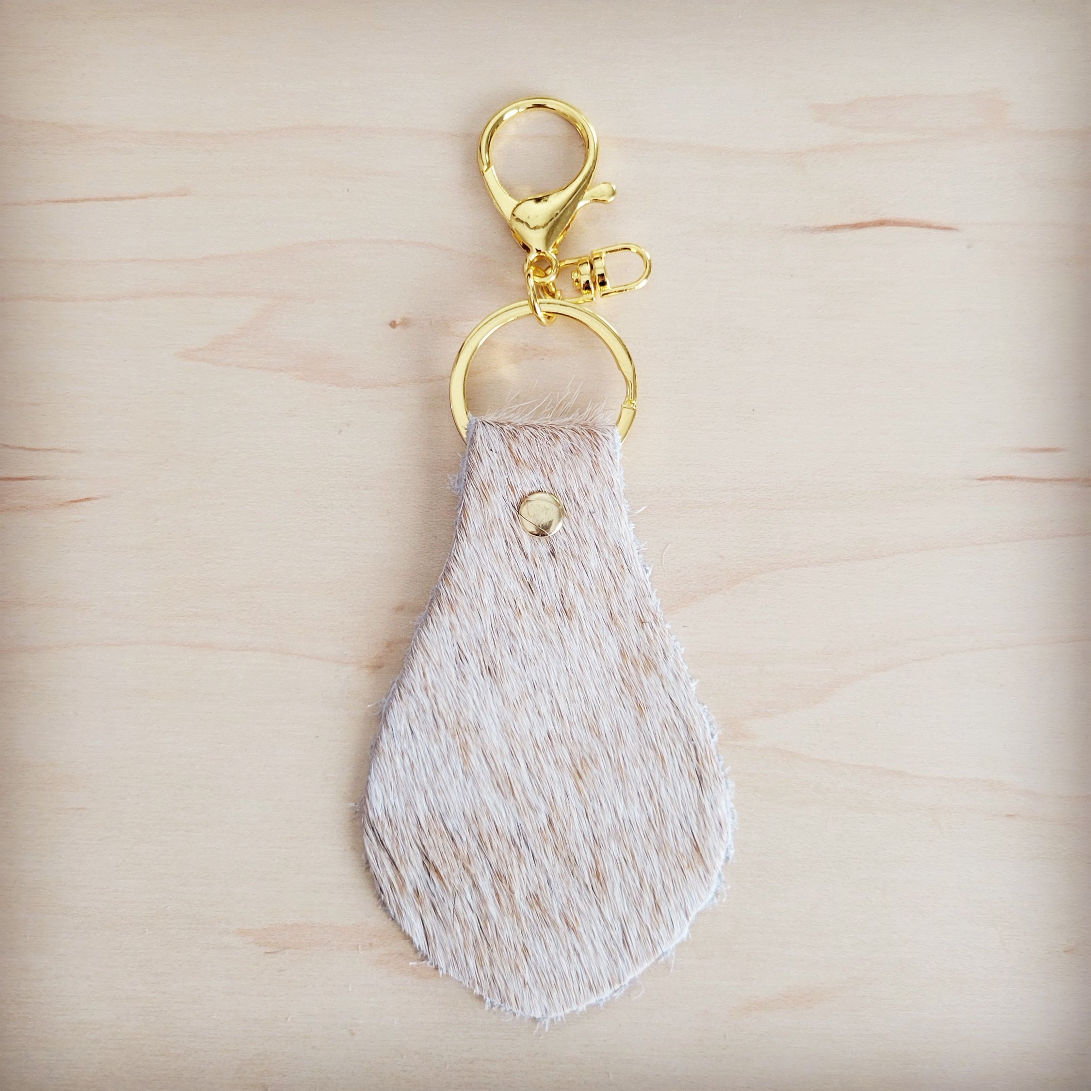 Two light tan hair-on-hide leather key chains showing natural shade variation