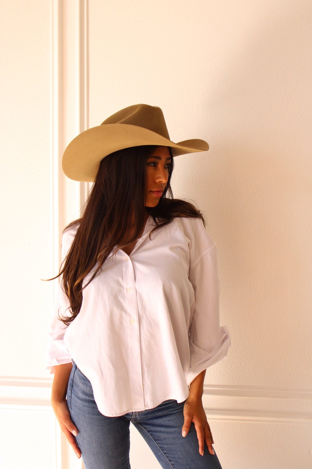 Model in a white shirt and jeans wearing the camel Wren merino wool cowboy hat, looking to the side