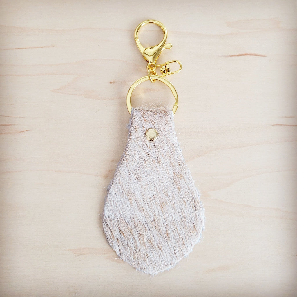 Light tan hair-on-hide key chain shown with the full hide it is cut from