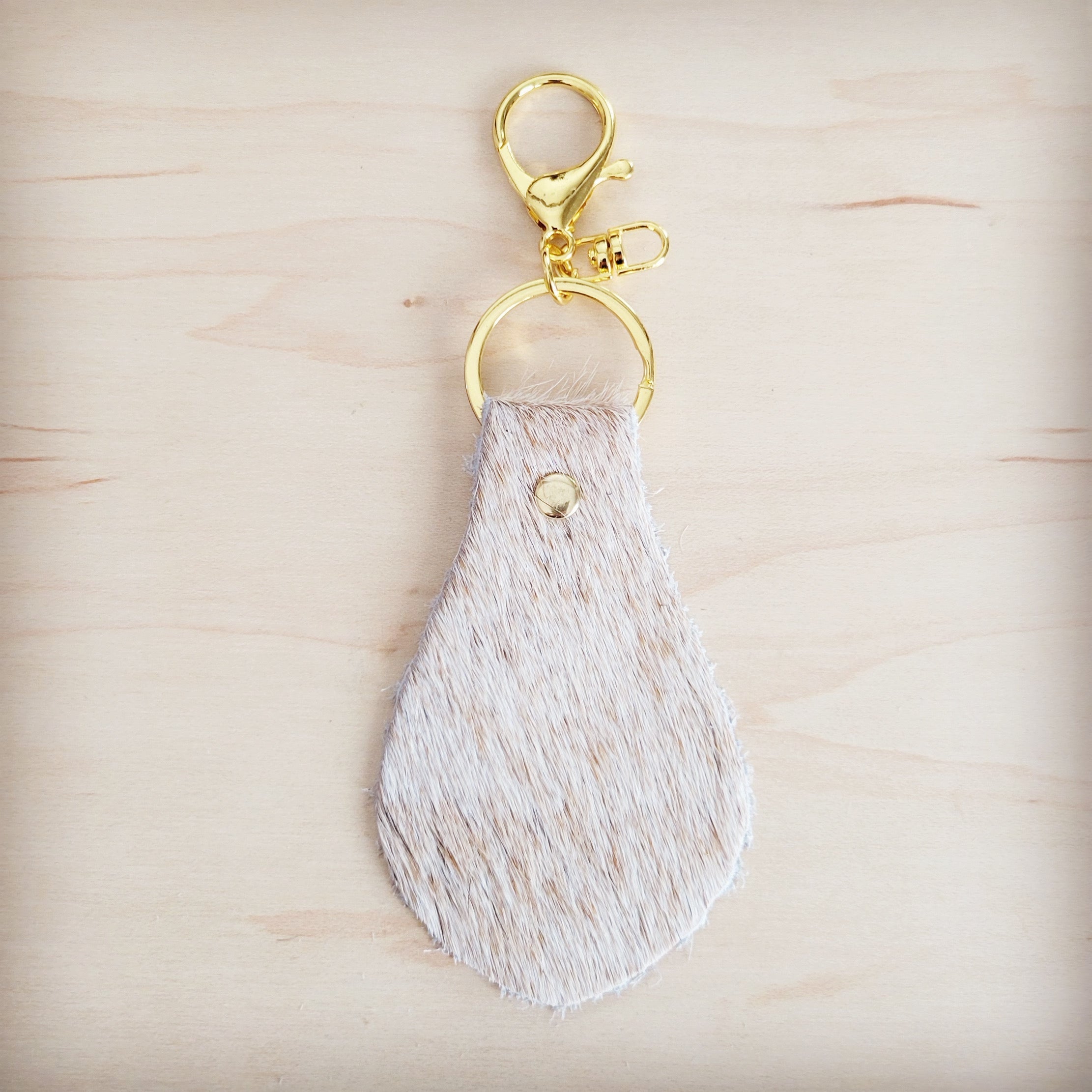 Light tan hair-on-hide key chain shown with the full hide it is cut from