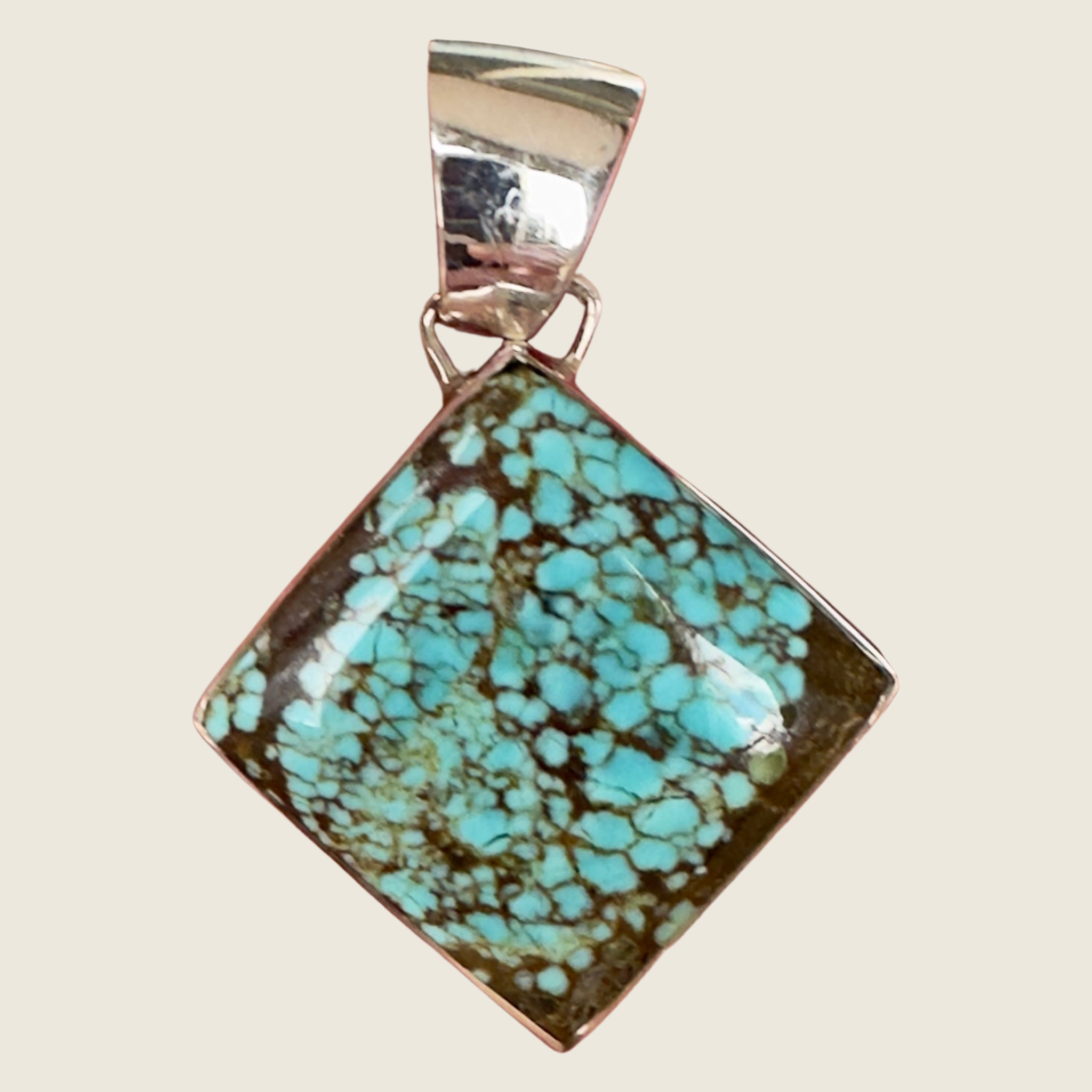 Number 8 spiderweb turquoise square pendant in sterling silver by Martinez, shown on a bone linen background