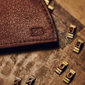 Brown leather wallet corner debossed with the initials Z S, beside brass type letters