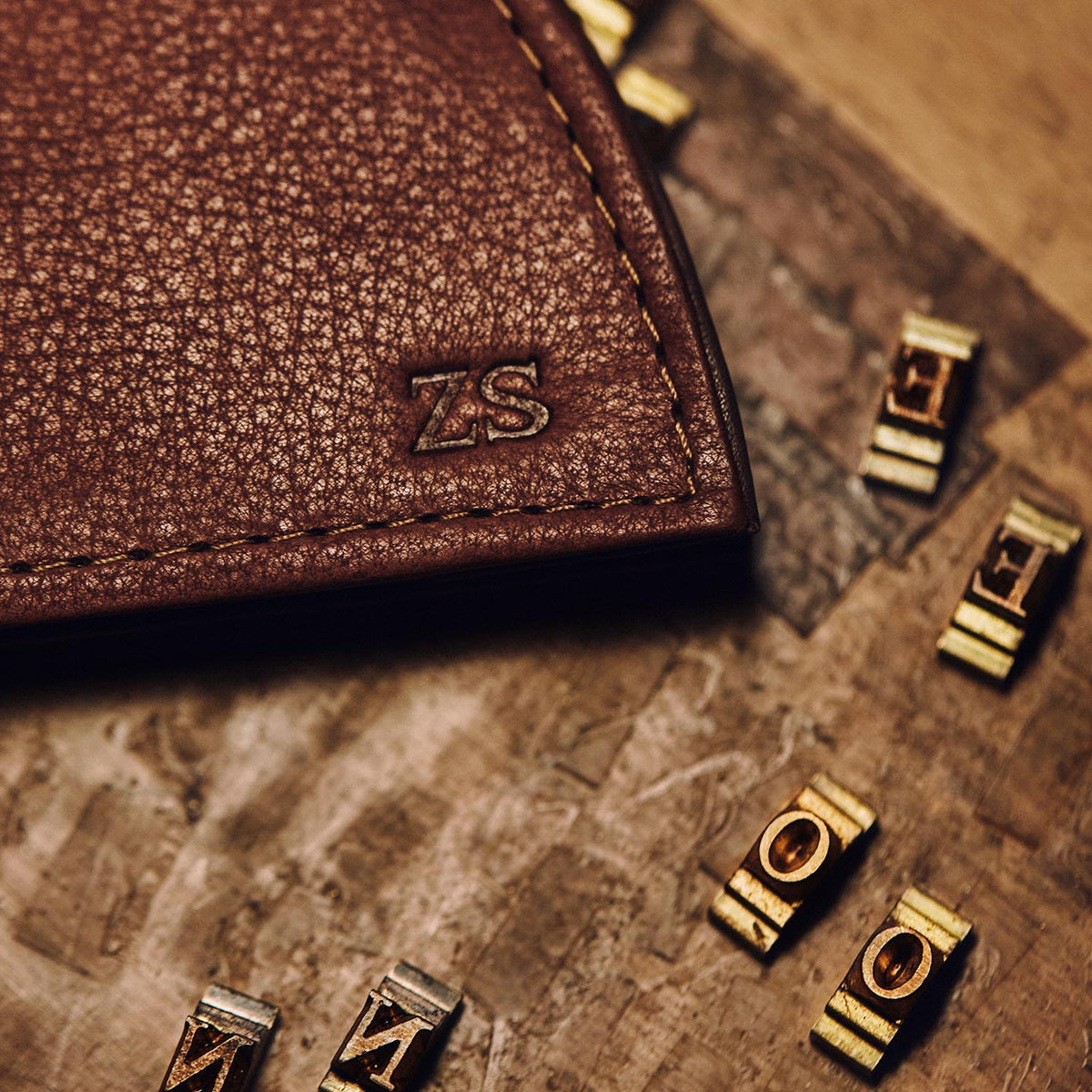 Brown leather wallet corner debossed with the initials Z S, beside brass type letters