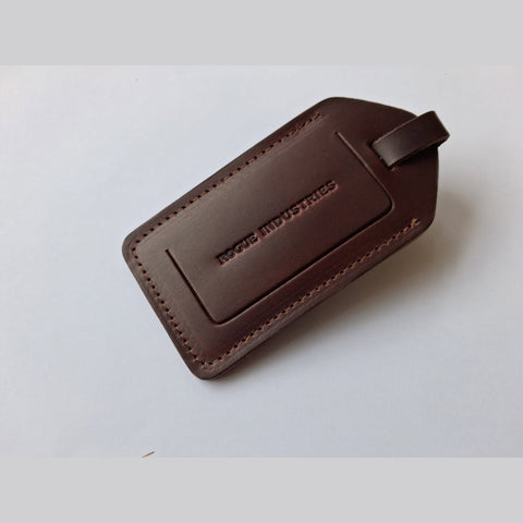 Dark brown leather luggage tag with the Rogue Industries mark debossed on the front panel