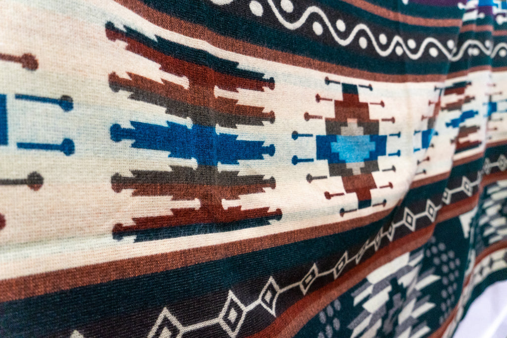 Wide close-up of the cream center band with blue and rust diamond motifs on the Evergreen alpaca blend blanket