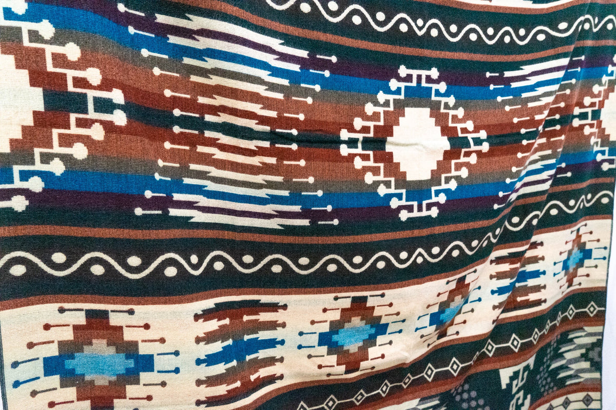 Detail of the woven geometric border and stepped diamonds on the forest green Evergreen alpaca blend blanket