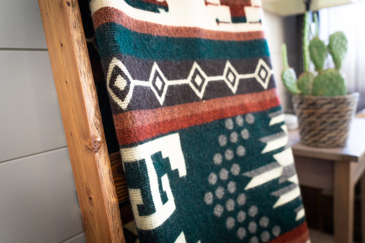 Close view of the rust, cream and white geometric pattern on the forest green Evergreen alpaca blend blanket
