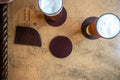 Burgundy leather coasters with cork backing on a nautical chart table with two beers