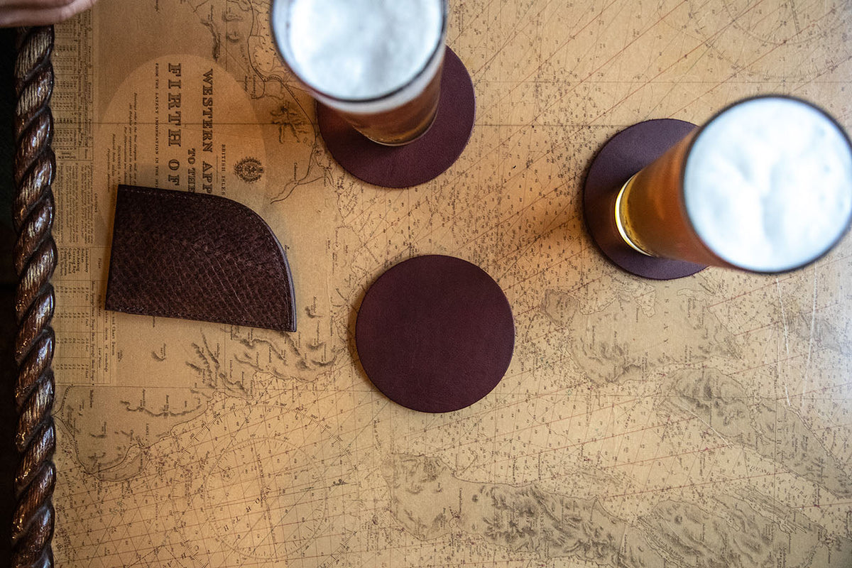 Burgundy leather coasters with cork backing on a nautical chart table with two beers
