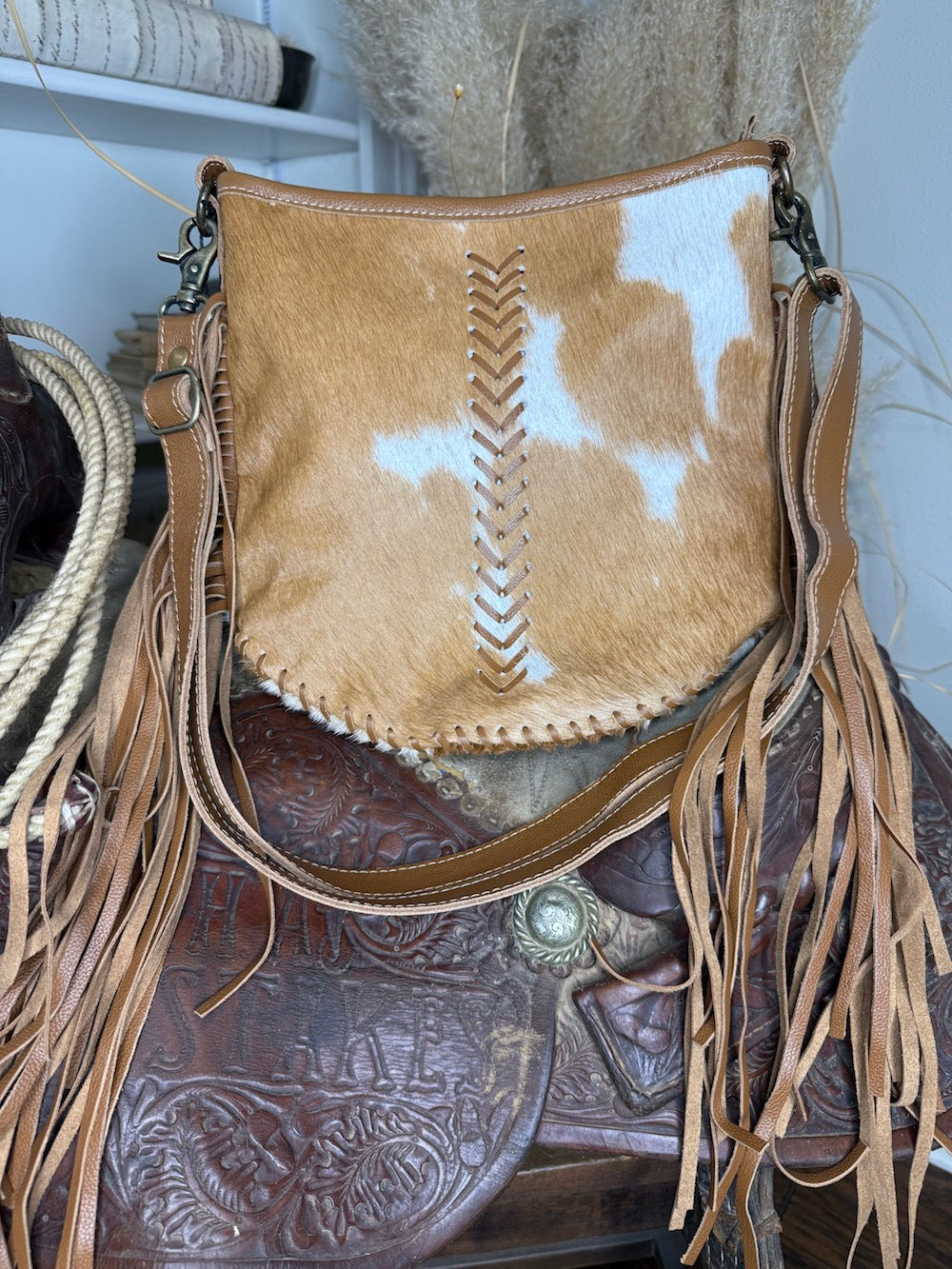 Western shoulder bag in caramel and white hair-on cowhide with tan leather chevron lacing and long leather fringe