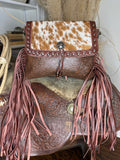 Western shoulder bag with a studded cowhide flap, floral tooled leather body and dusty rose leather fringe