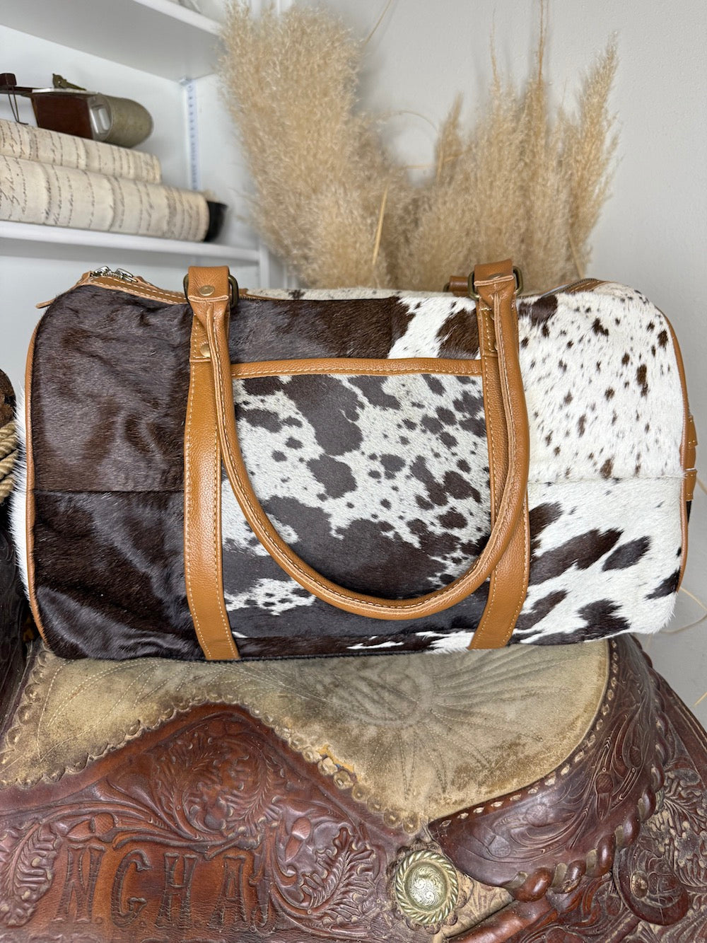 Patchwork hair-on cowhide weekender duffel bag in black, brown and white with tan leather handles