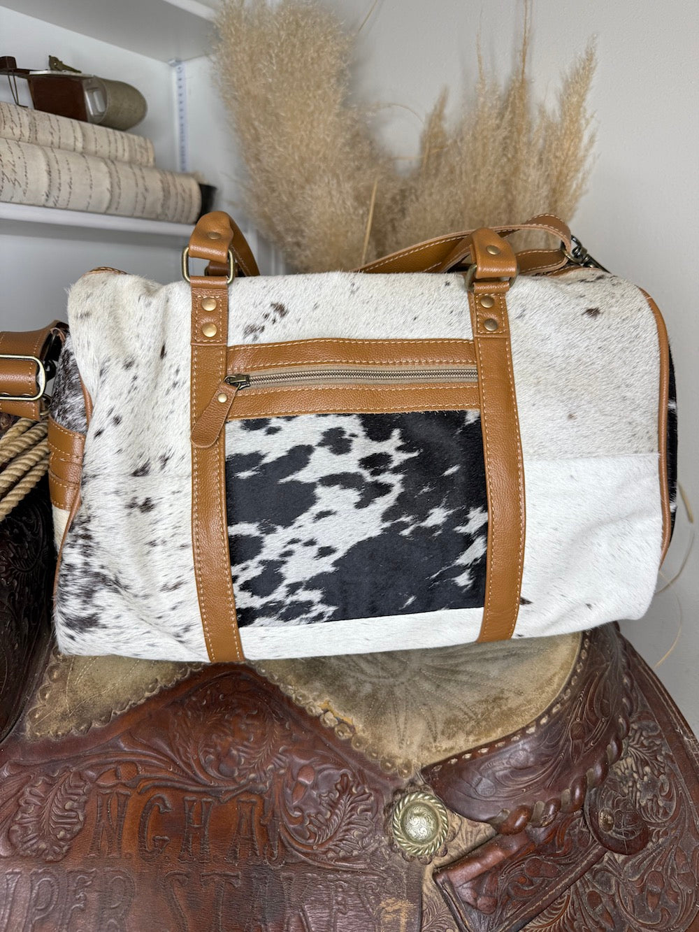 Second view of the patchwork cowhide weekender duffel showing the speckled hide panel and exterior zip pocket