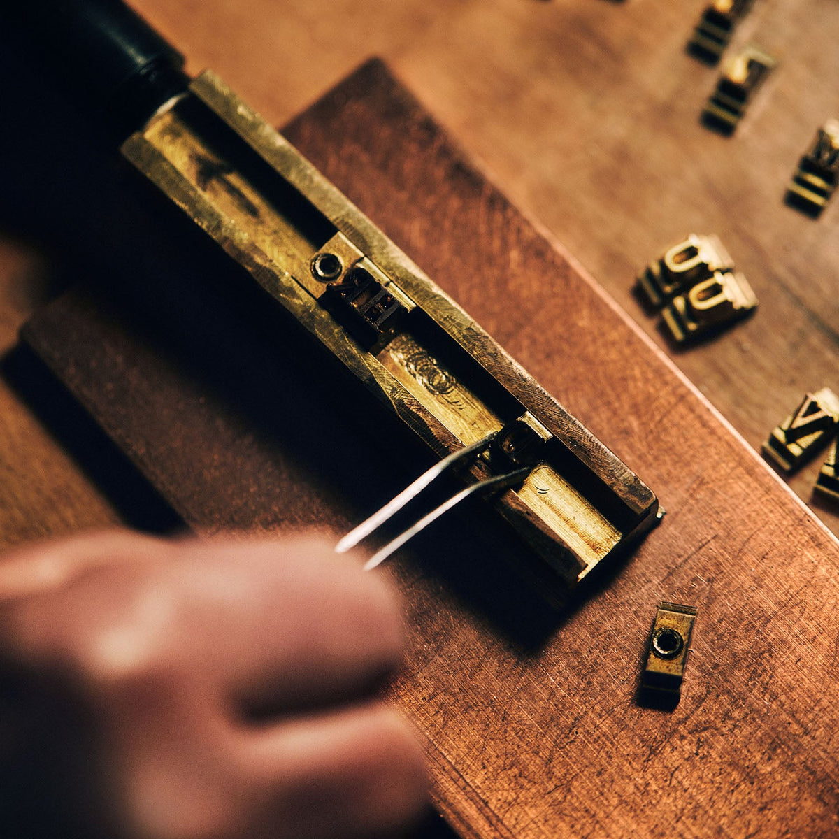 Brass monogram dies being set into a heated press on a workshop bench