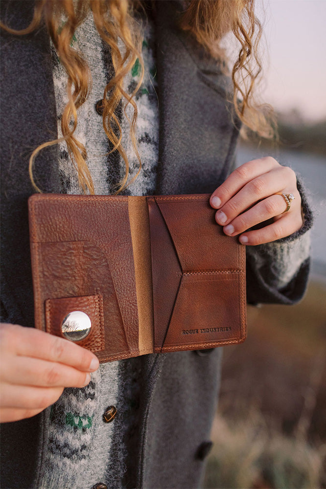 Bison leather passport holder open, showing the AirTag pocket and the Rogue Industries stamp