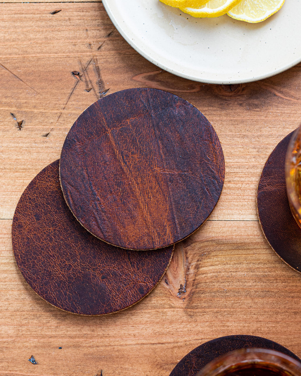 Two moose leather coasters stacked, showing the cork backing and reddish brown grain