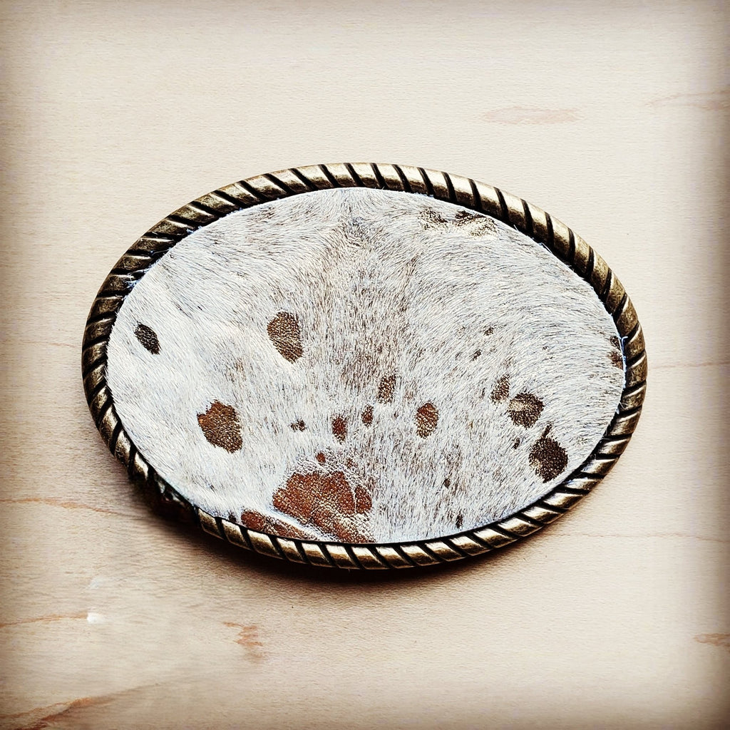 Oval belt buckle faced in white spotted hair on hide with an antique gold rope edge