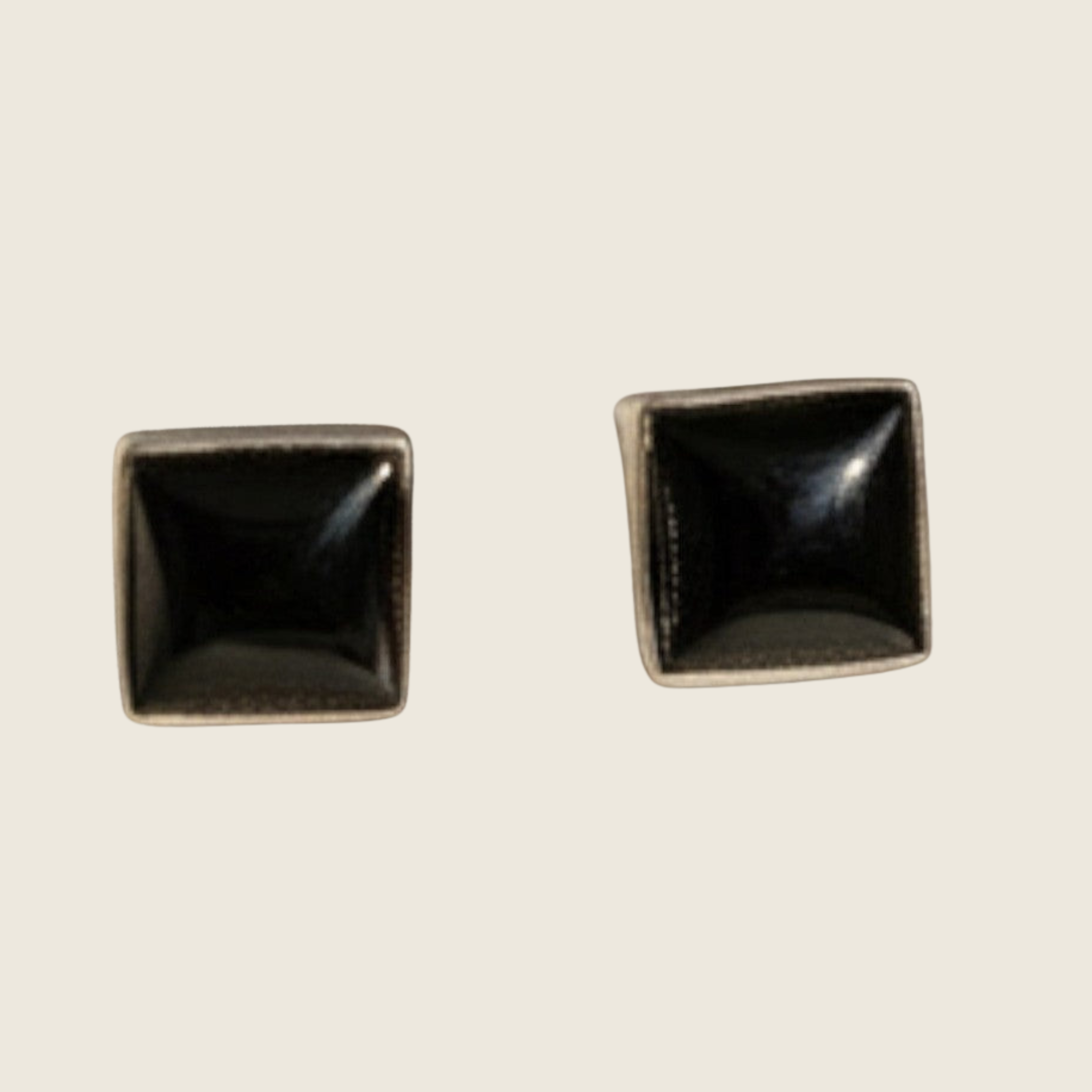Black onyx square stud earrings in sterling silver, shown on a bone linen background