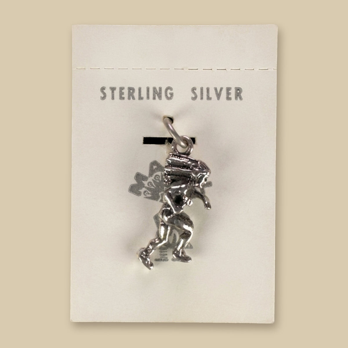 Dancer in Headdress Charm in Sterling Silver, Vintage Maisel's New Old Stock, shown on a sand background