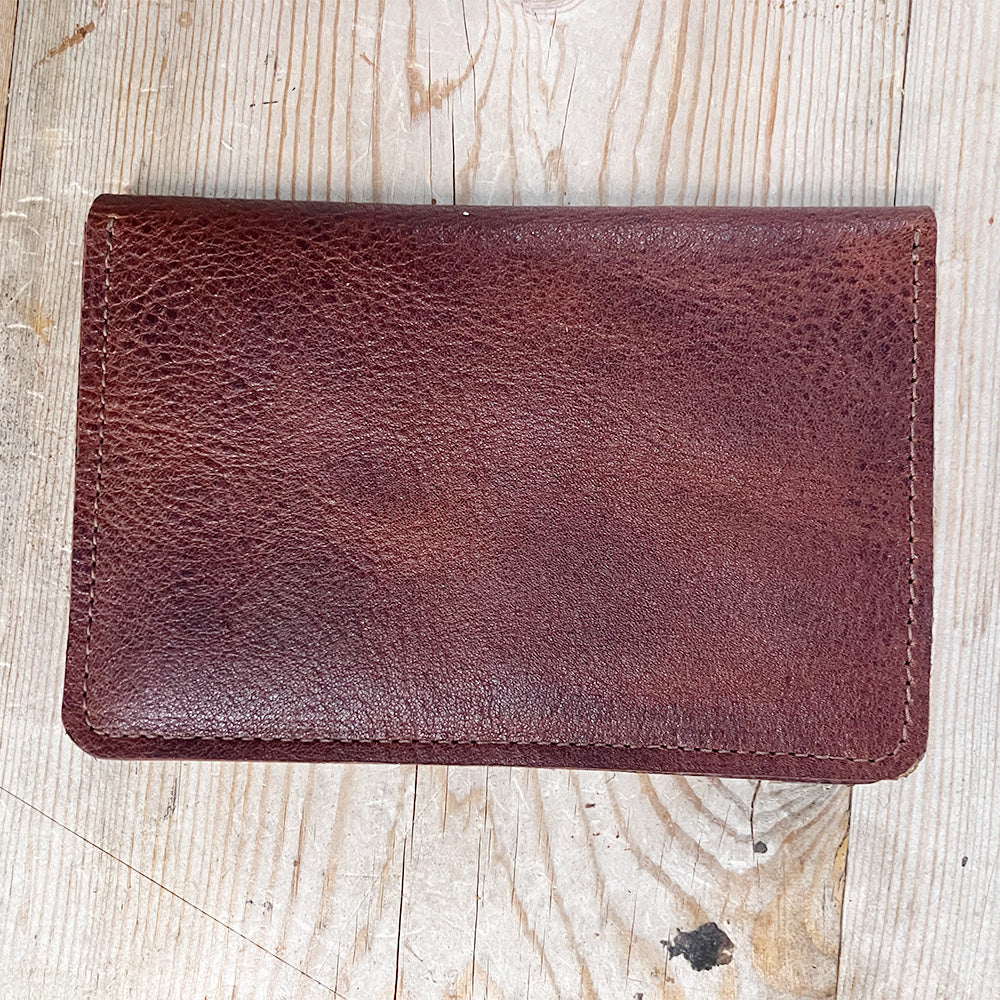 Bison leather passport holder closed, flat on weathered wood