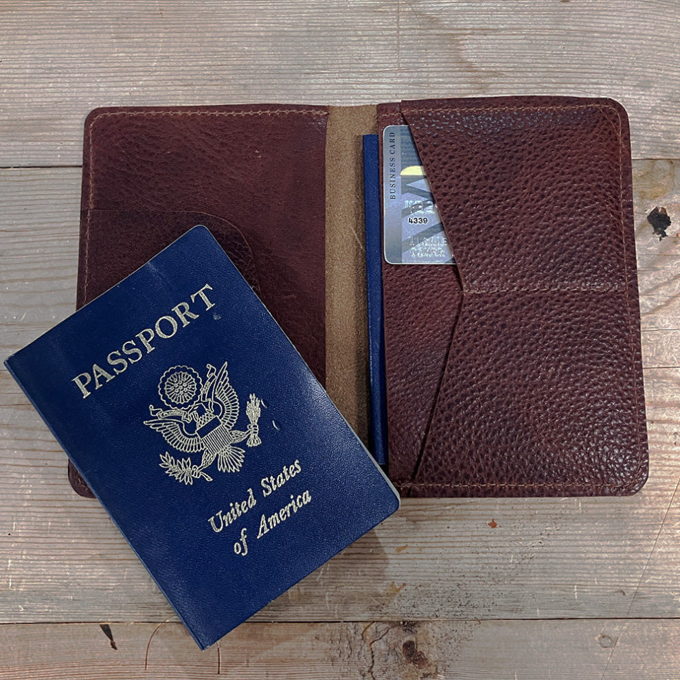 Bison leather passport holder open on weathered wood with a US passport and a card in the pocket