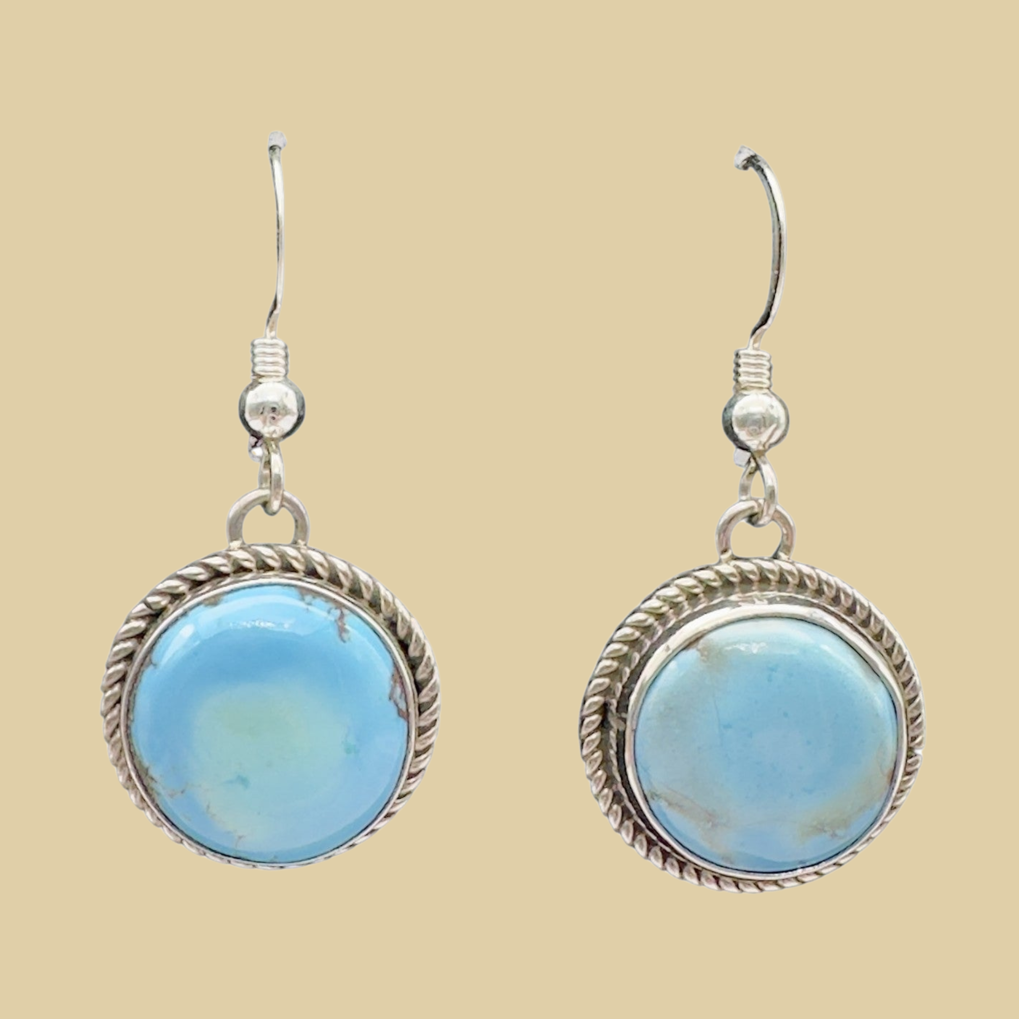 Golden Hills Turquoise Earrings in Sterling Silver, shown on a desert plaster background