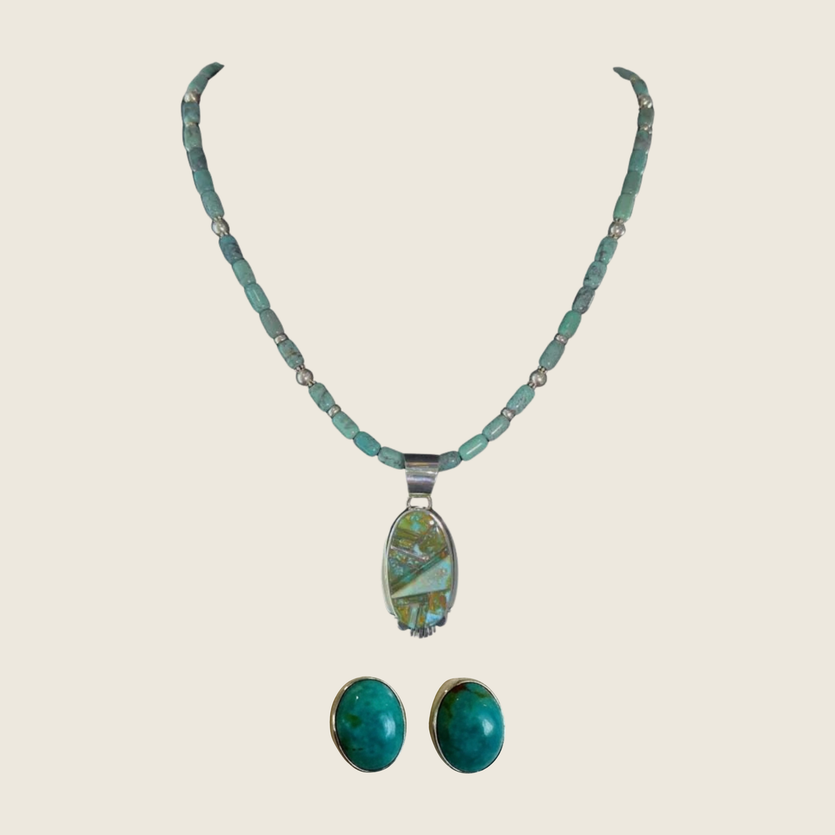 Green turquoise pendant and oval turquoise stud earrings jewelry set in sterling silver, shown on a bone linen background