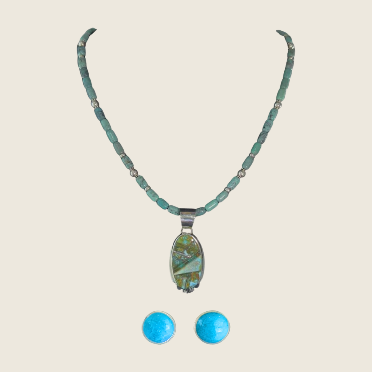 Green turquoise pendant and turquoise stud earrings jewelry set in sterling silver, shown on a bone linen background