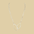 Leaf pendant necklace in sterling silver by Grace Chin, shown on a desert plaster background