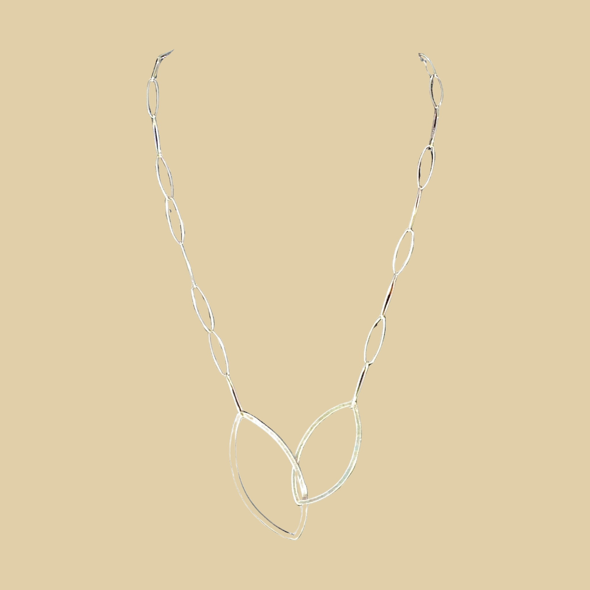 Leaf pendant necklace in sterling silver by Grace Chin, shown on a desert plaster background