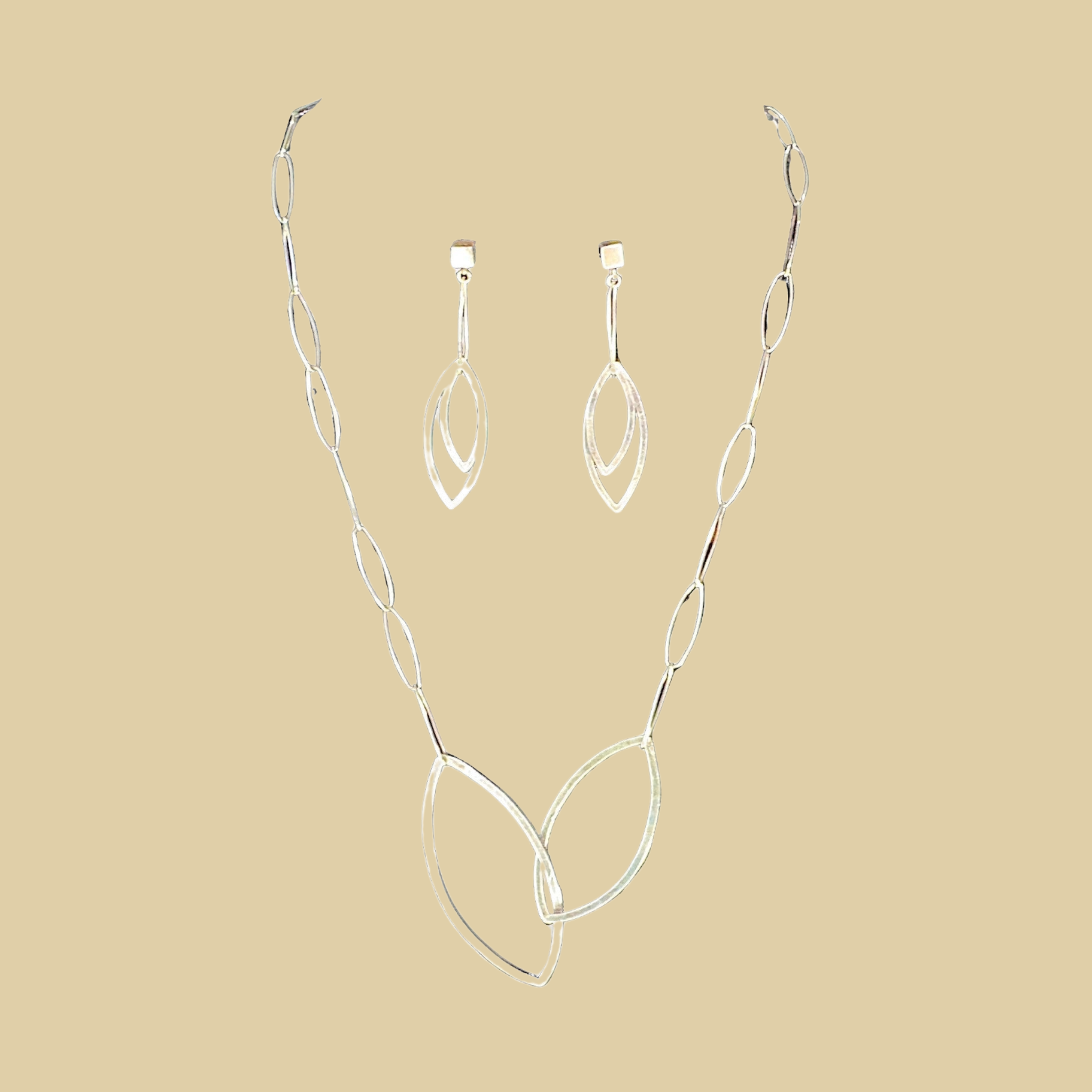 Leaf necklace and earrings jewelry set in sterling silver by Grace Chin, shown on a desert plaster background