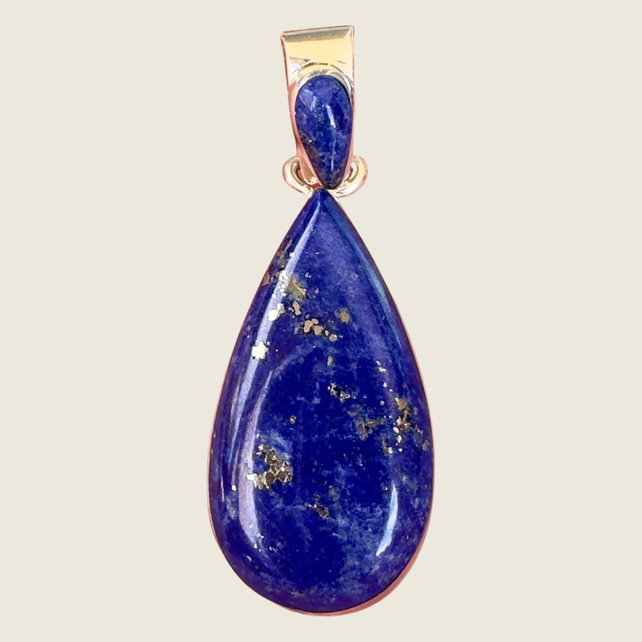 Lapis lazuli teardrop pendant in sterling silver by Martinez, shown on a bone linen background