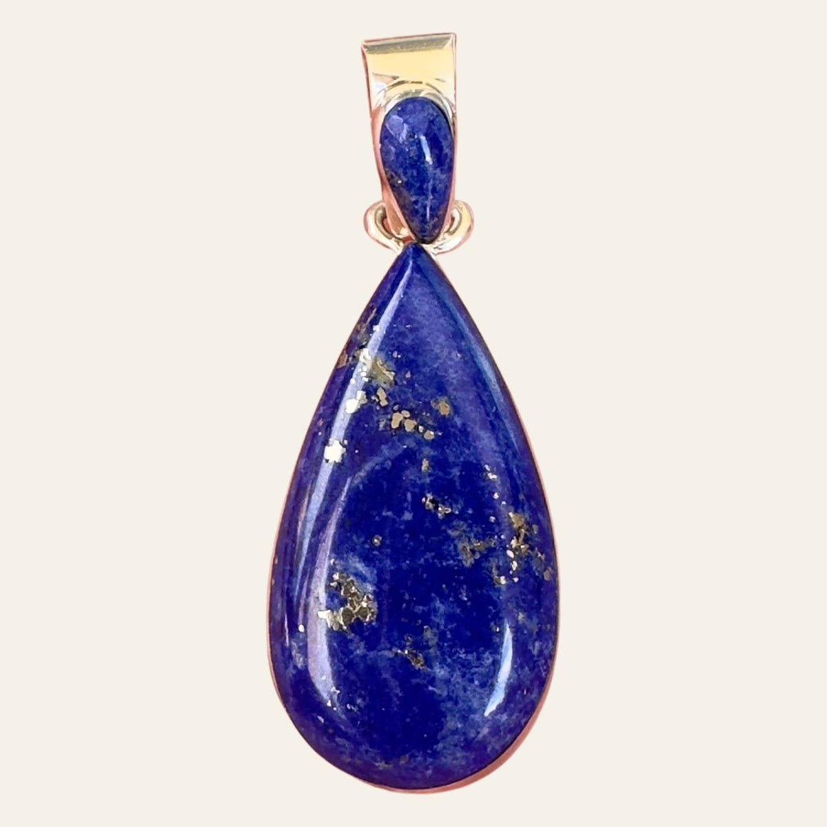 Lapis Lazuli Teardrop Pendant in Sterling Silver, by Martinez, shown on a cream background