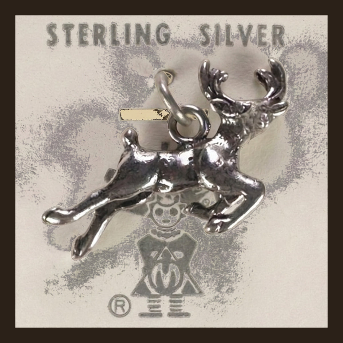 Leaping Elk Charm in Sterling Silver, Vintage Maisel's New Old Stock, shown on an espresso background