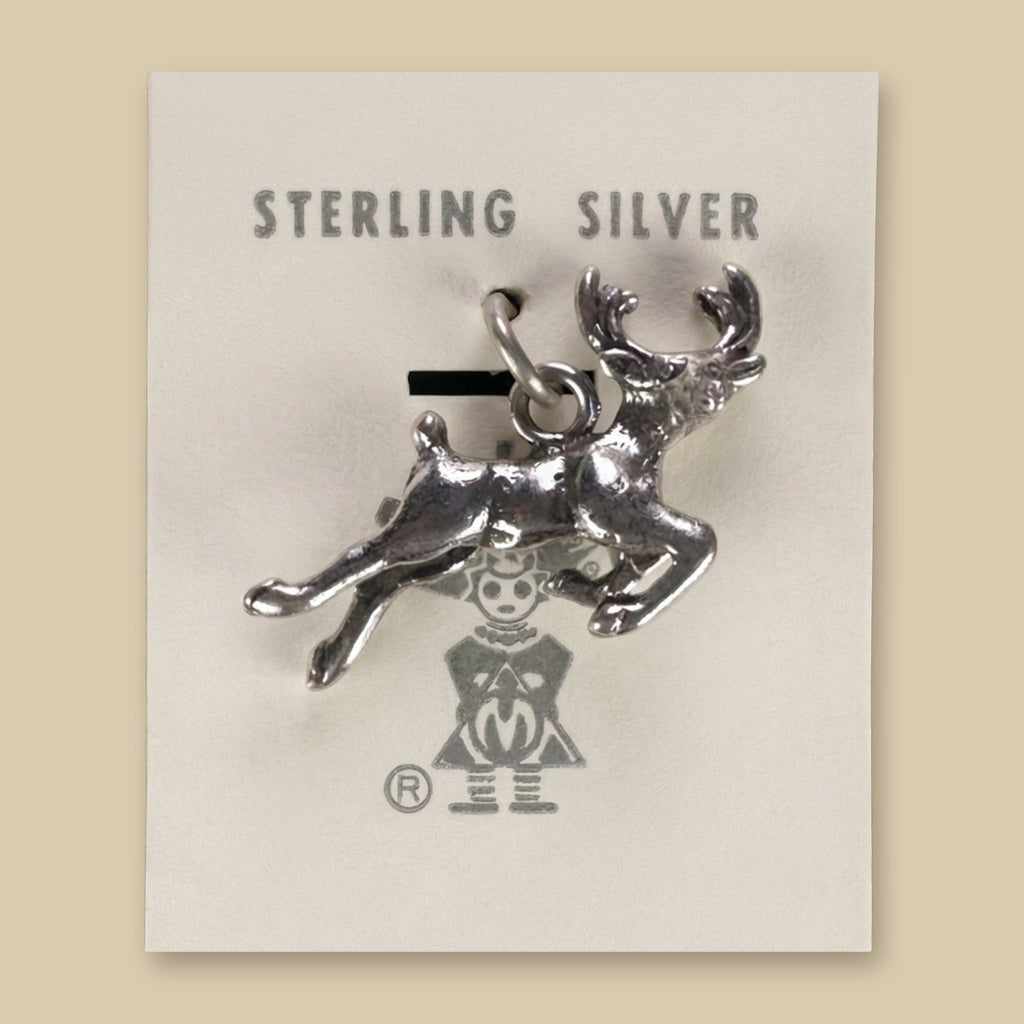 Leaping Elk Charm in Sterling Silver, Vintage Maisel's New Old Stock, shown on a sand background