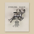 Leaping Elk Charm in Sterling Silver, Vintage Maisel's New Old Stock, shown on a sand background