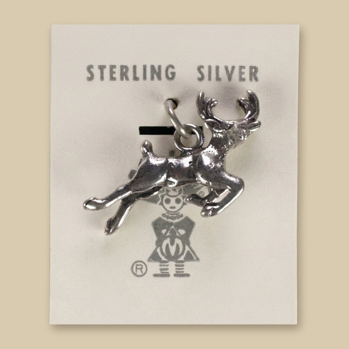 Leaping Elk Charm in Sterling Silver, Vintage Maisel's New Old Stock, shown on a sand background