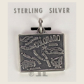 Vintage Maisel's sterling silver Colorado state map charm, shown on a bone linen background