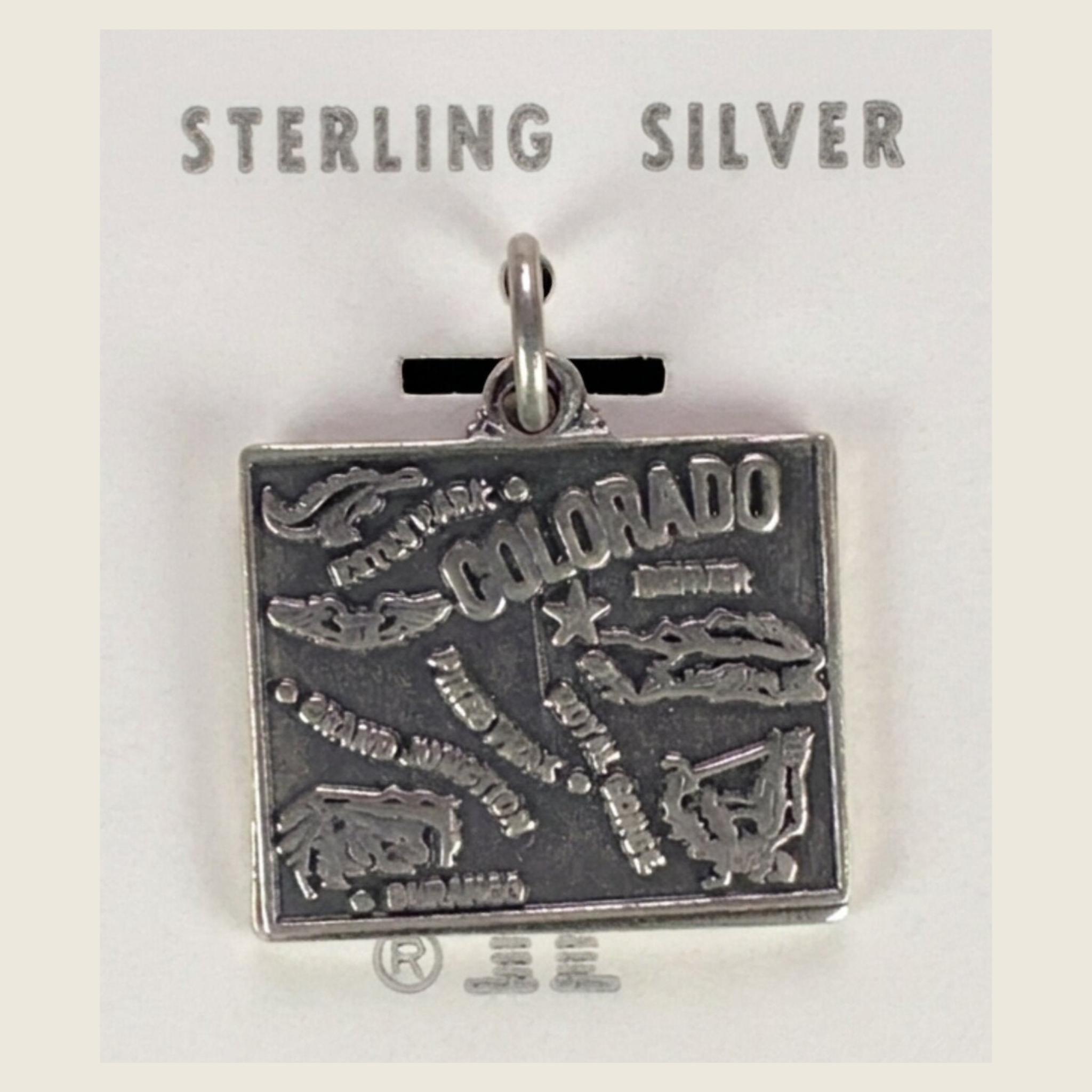 Vintage Maisel's sterling silver Colorado state map charm, shown on a bone linen background