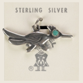 Vintage Maisel's sterling silver roadrunner charm with turquoise eye, shown on a bone linen background