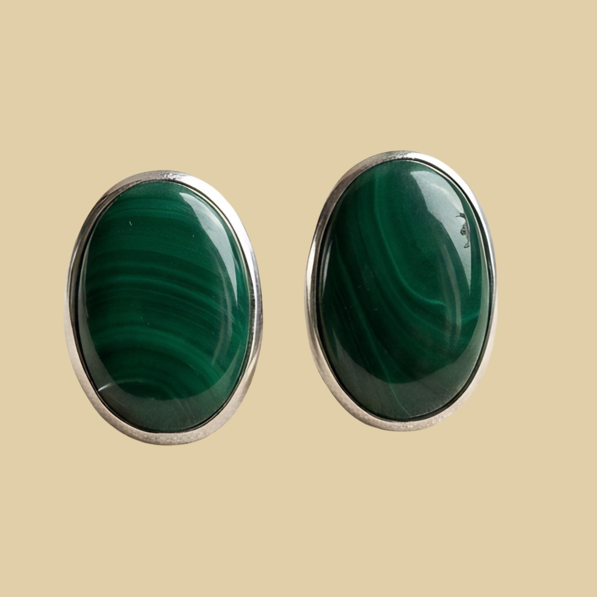 Malachite Oval Stud Earrings in Sterling Silver, shown on a desert plaster background