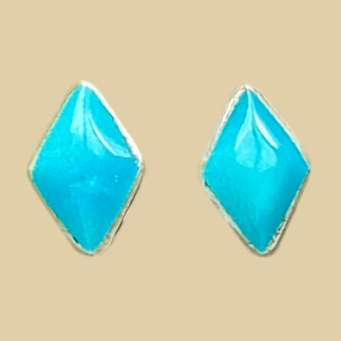 Natural Turquoise Kite Stud Earrings in Sterling Silver, shown on a desert plaster background
