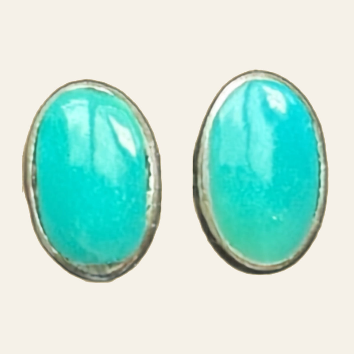 Natural Turquoise Oval Stud Earrings in Sterling Silver, shown on a cream background