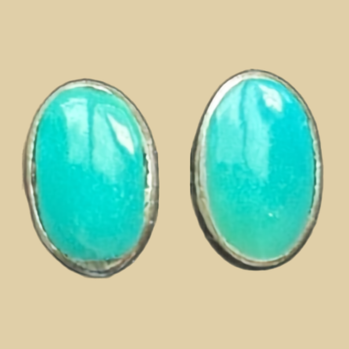 Natural Turquoise Oval Stud Earrings in Sterling Silver, shown on a desert plaster background